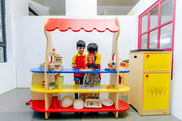 Two young children play joyfully with a colorful wooden ice cream set