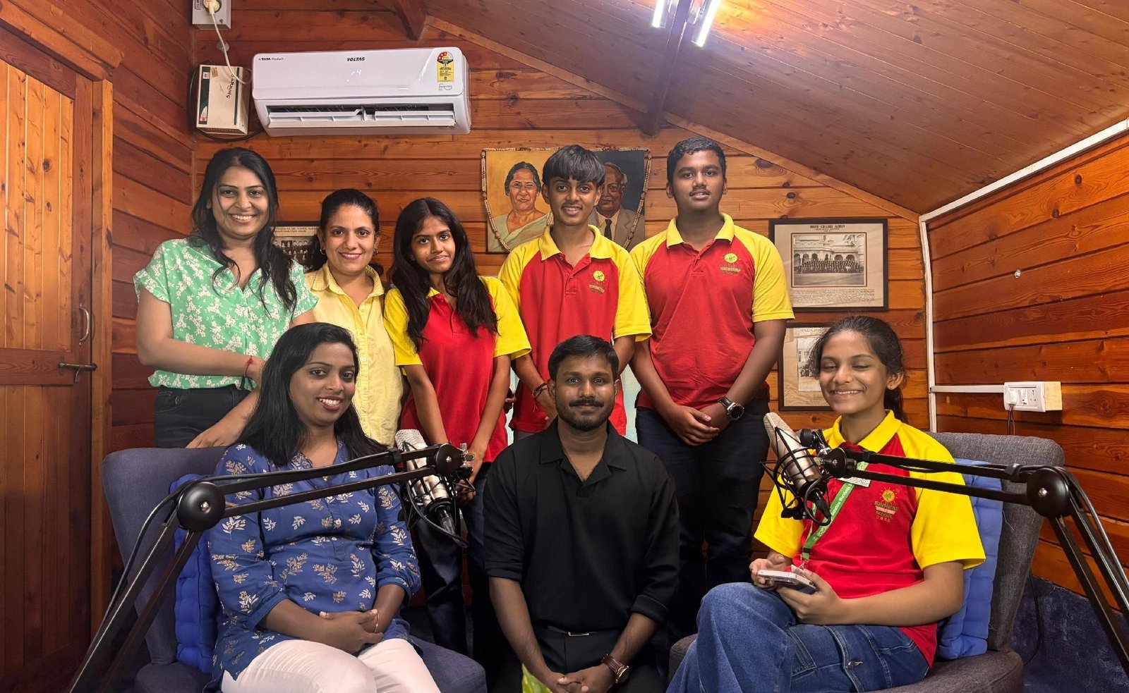 Teachers and students in a podcast studio with two microphone stands